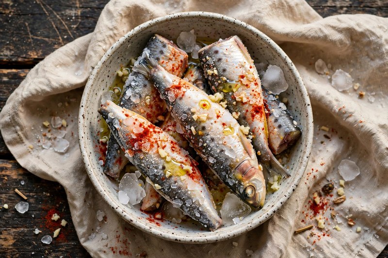 TK Sardinen werden mit Gewürzen vermengt – die Gewürze haften gut am gefrorenen Fisch