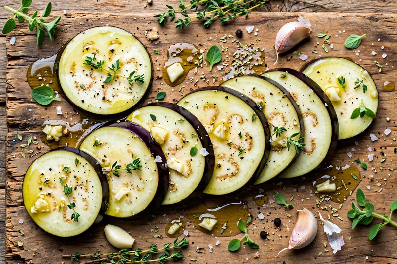 Auberginen-Scheiben mit Olivenöl, Knoblauch und mediterranen Kräutern mariniert