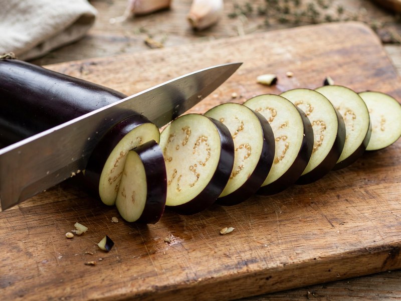 Aubergine wird in 1 cm dicke Scheiben geschnitten